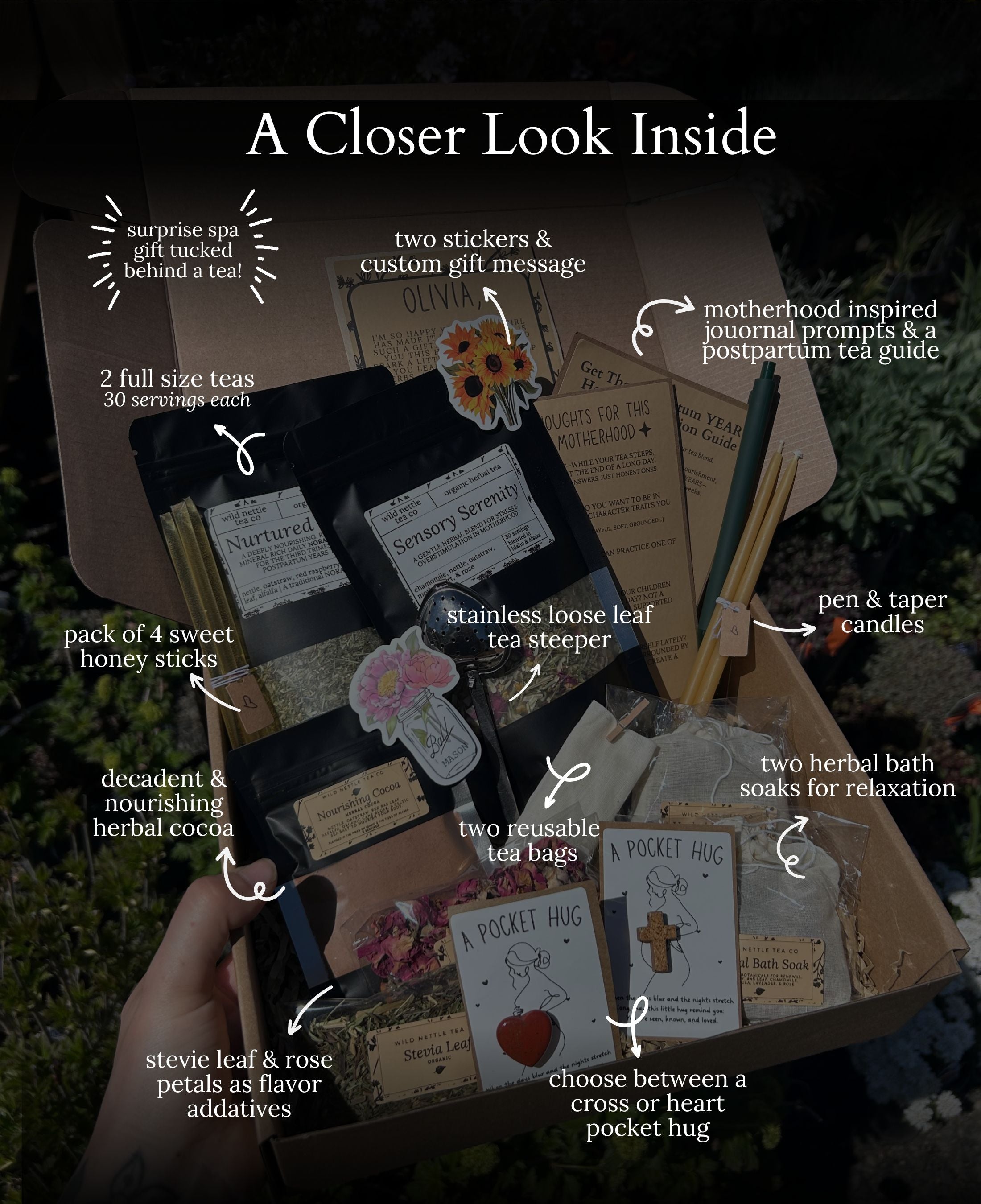 An open postpartum care package filled with tea and self-care items, shown with handwritten callouts and arrows pointing to specific contents such as a tea bag, stickers, candle, soap, and journal. A hand is visible holding the box, and the background is an outdoor garden setting.