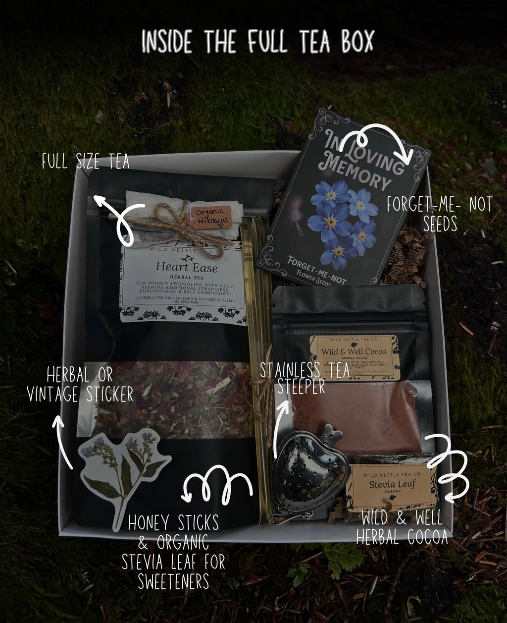 A curated sympathy gift tea gift basket labeled 'INSIDE THE FULL TEA BOX' shown from above on a dark mossy surface. The box contains multiple tea-related items and accessories: a full-size tea packet, a vintage-style tea sticker, a stainless steel tea steeping pot, wild & well herbal cocoa, forget-me-not seeds, and honey sticks & organic stevia leaf for sweeteners.